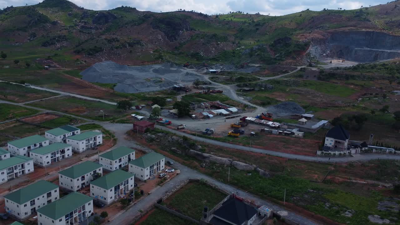 Beautiful aerial pan of Abuja's vibrant mix of housing and quarry. Lush greenery, and residential blocks contrast with industrial areas, creating a dynamic scene. Real estate development in Africa