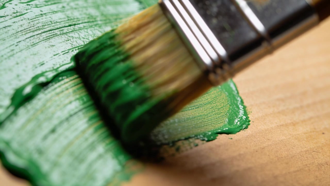 Dragging flat brush metal ferrule natural bristles on table pulling paint from patch to smooth area