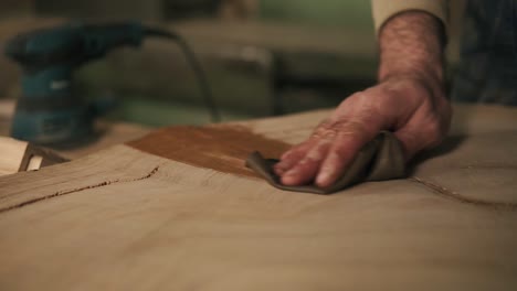 the carpenter with a rag in his hand processes the wood with oil after grindering