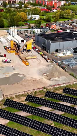 a solar farm is located beside modern industrial and corporate buildings in latvia, highlighting sustainable power generation in an innovative business environment - aerial vertical shot