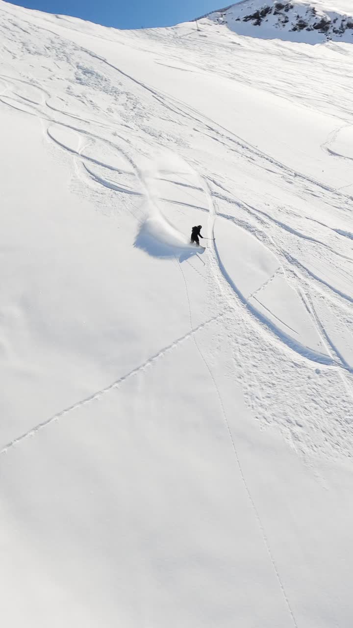 An exhilarating FPV drone shot capturing a snowboarder carving through deep powder snow on a bright winter day. The dynamic perspective highlights the snowboarder in the untouched snowy terrain