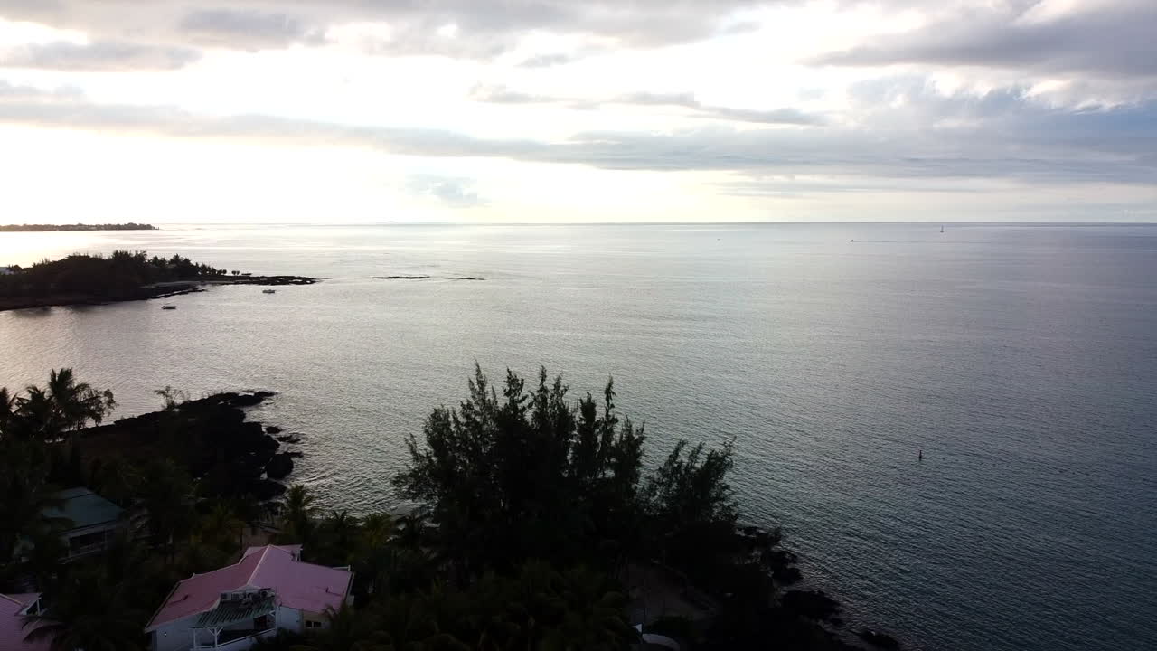 흐린 일몰 동안 공중 역방향 비행 오버 헤드 인도양, 해안 및 빌라