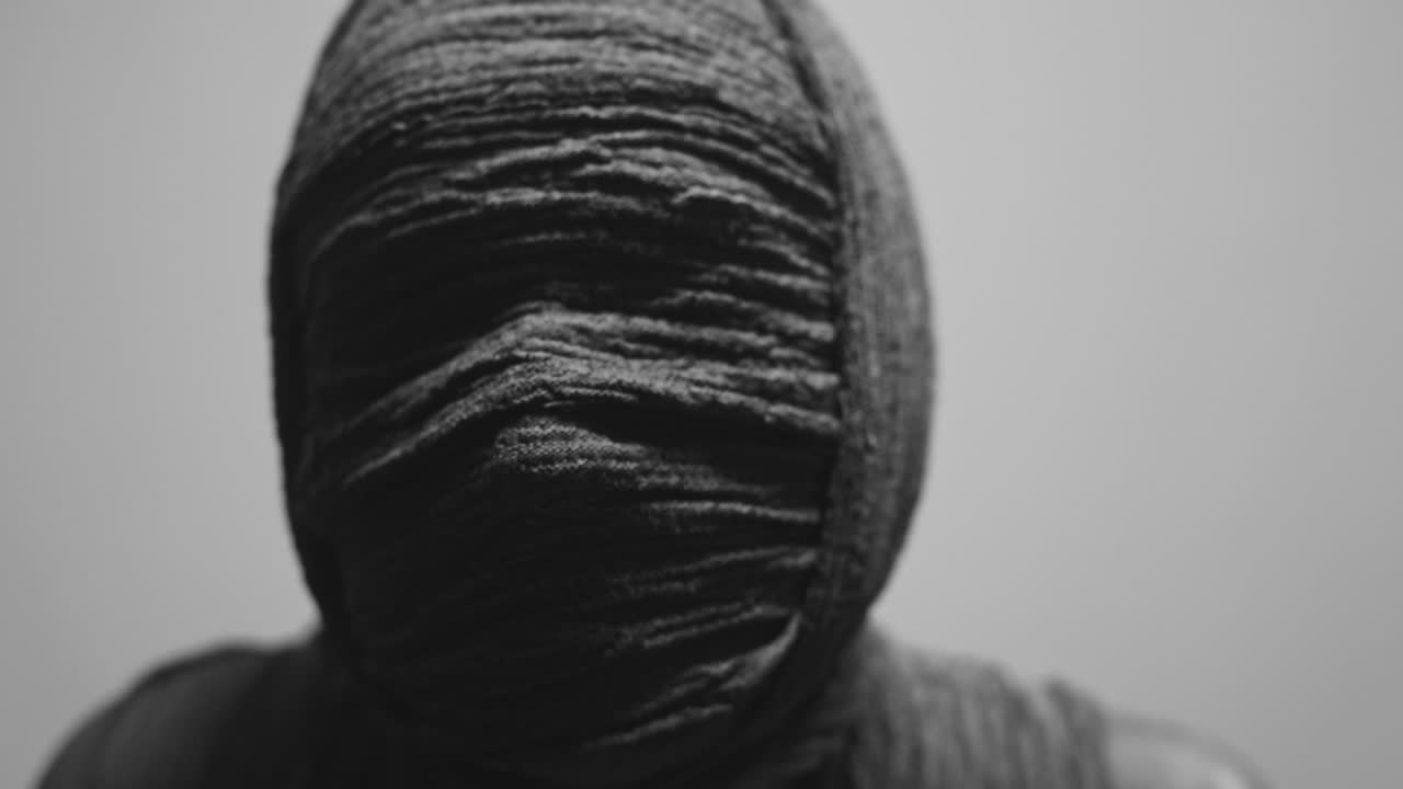 A mummy of a woman on a white backdrop looks into the camera