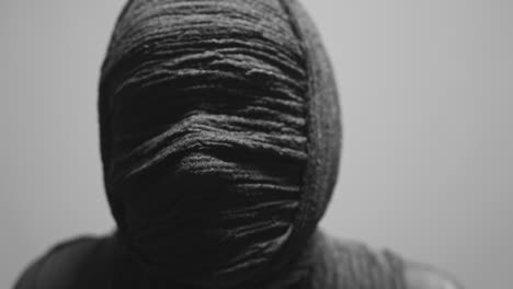 a mummy of a woman on a white backdrop looks into the camera