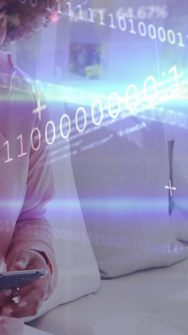 Video verticale: Donna che tocca il telefono sul divano, attivando un'interfaccia HUD binaria sovrapposta e mostrando una demo tecnologica.