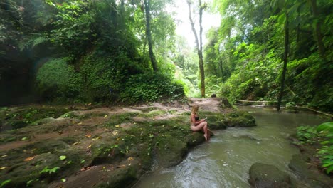 hermosa mujer rubia relajándose en la naturaleza de bali con una gran cascada en el fondo