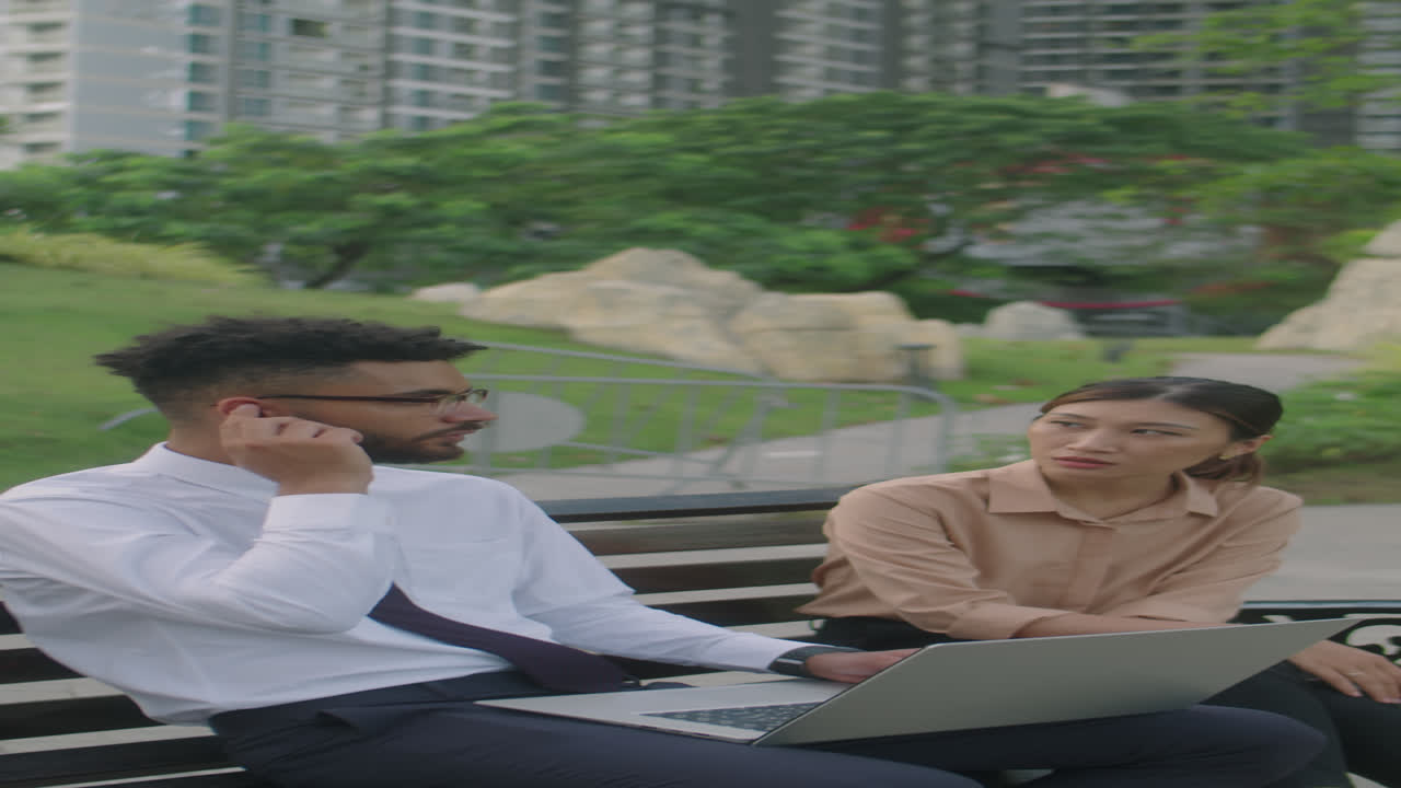 Business Partners Using Laptop and Talking in Park