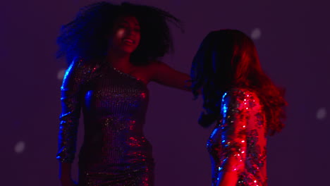 cerca de dos mujeres en un bar de club nocturno o discoteca bailando con confeti cayendo y luces brillantes