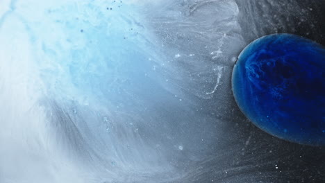 abstract close-up of ink mixing in water with dark blue and white hues blending together