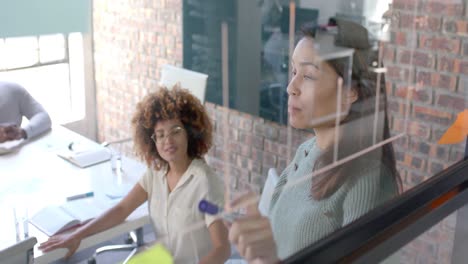 Diverse-male-and-female-colleagues-in-discussion,-brainstorming-at-glass-wall-in-office,-slow-motion