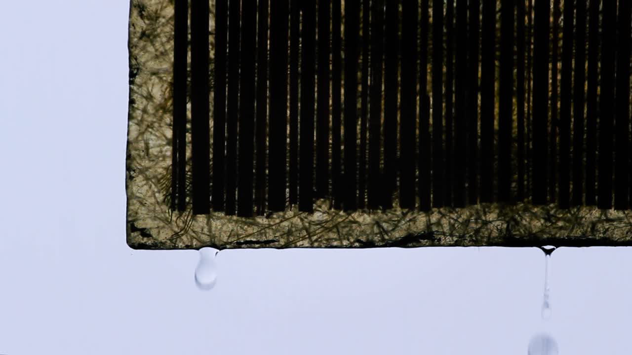 Close-up of wet roof shade edge during rainy weather. Textured surface with cloudy sky in background. Calm and minimal rain vibe