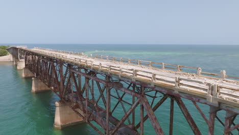 aerial trucking pan along decrepit broken run down bridge in middle of ocean