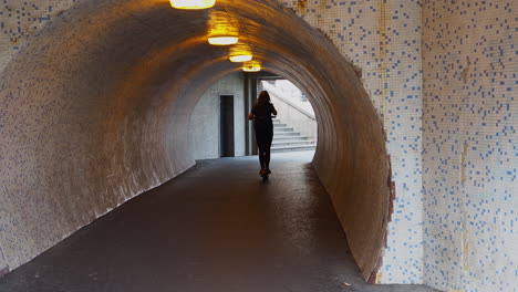 girl with electric scooter drive through tunnel underpass