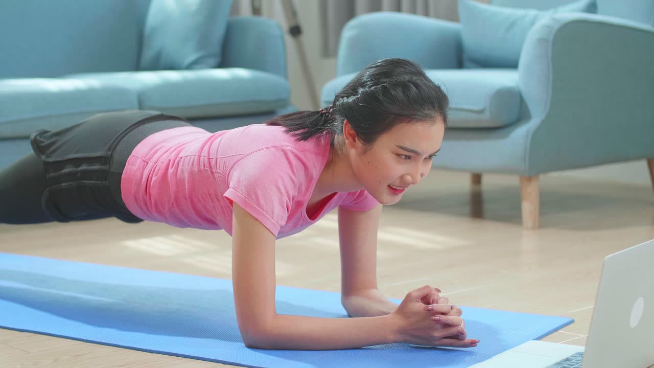 Asian Woman Doing Plank And Watching Online Tutorials On Laptop, Training In Living Room