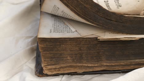 male hand flicks through pages of aged holy bible on table