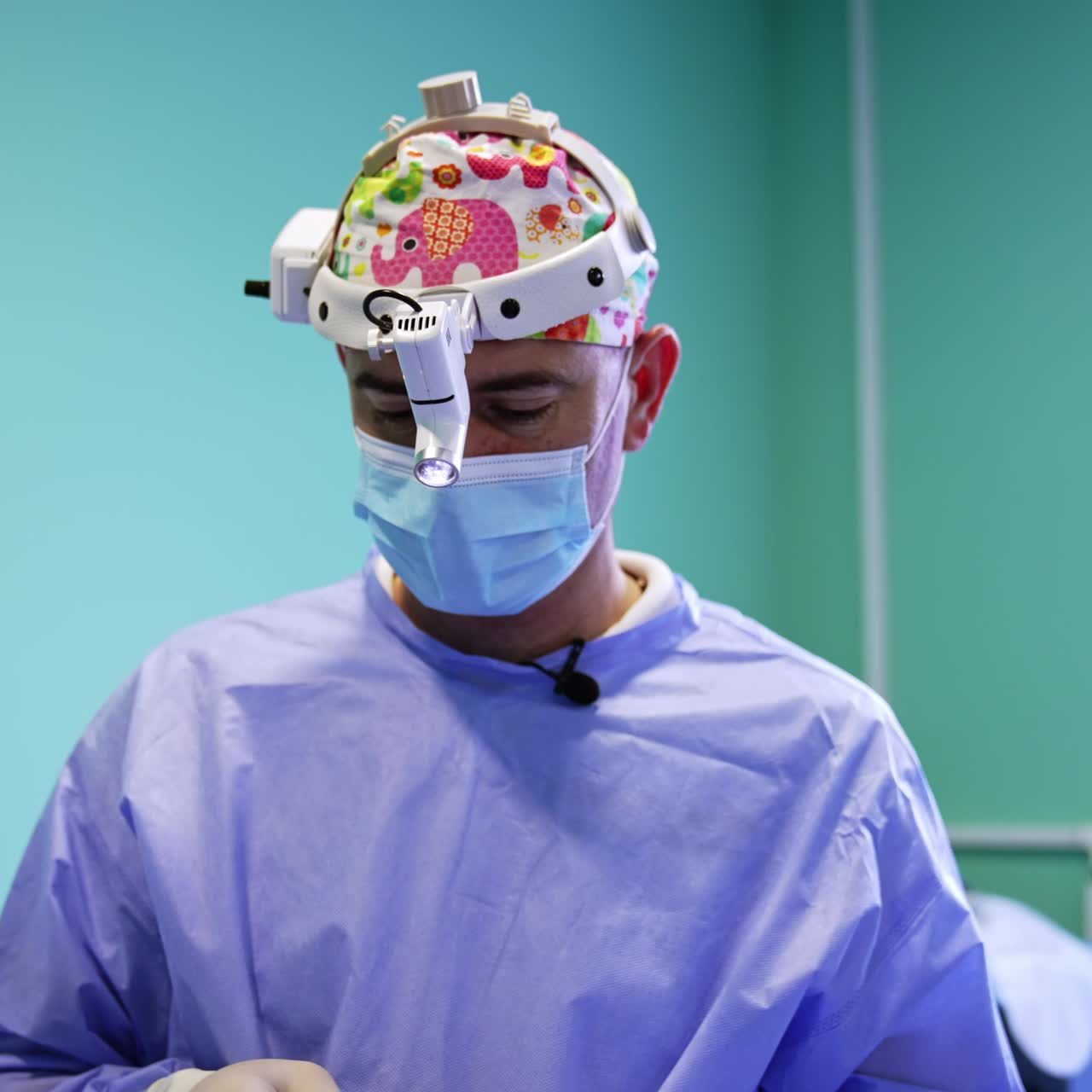 Confident mature healthcare specialist in operational room. Surgeon with headlight using bandage at work