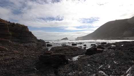 A-fisherman-walks-out-onto-a-reef-ledge-and-looks-at-the-wild-coastline-in-southern-Australia