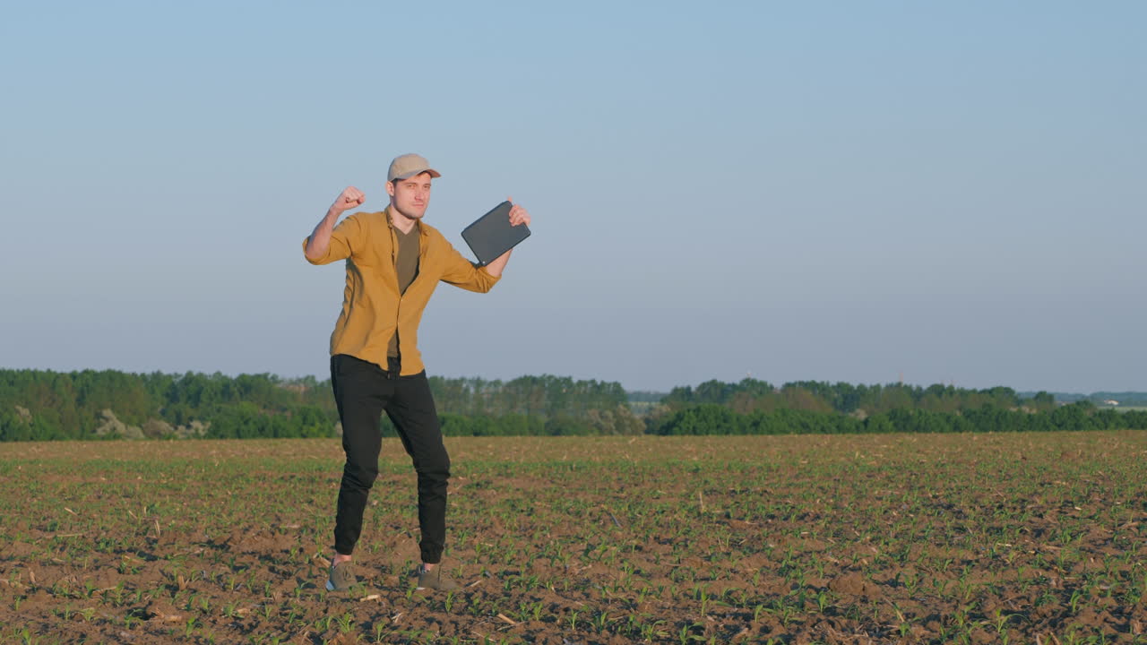 фермер празднует успех в поле с планшетом