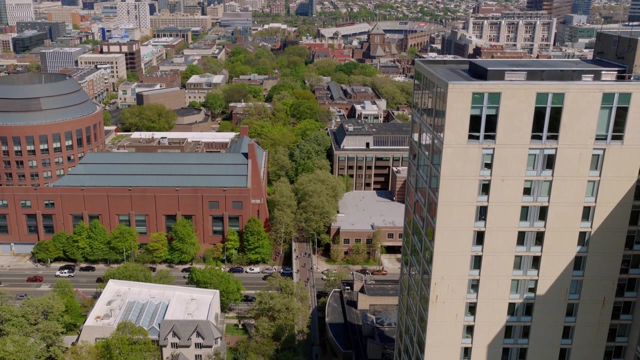 Veduta aerea con drone del campus dell'Università della Pennsylvania, con grattacieli, un edificio a cupola, viali alberati e i quartieri circostanti di West Philadelphia.