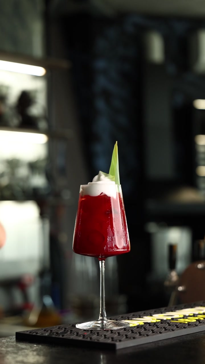 Bartender che aggiunge spuma di panna montata a un cocktail rosso