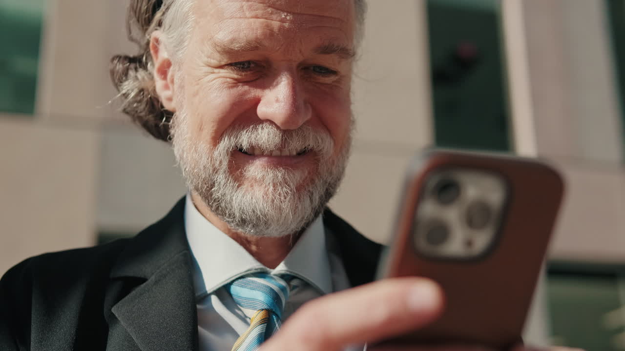 Smiling Businessman Checks Phone in the City