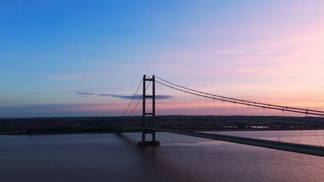 Die-Silhouette-Des-Sonnenuntergangs:-Die-Humber-Bridge-Steht-Im-Mittelpunkt,-Während-Autos-Aus-Der-Sicht-Einer-Luftdrohne-Ein-Ruhiges-Bild-Zeichnen