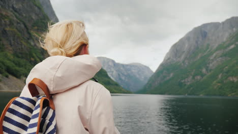 a tourist with a flag of norway stands on the nose of a cruise ship journey through the picturesque