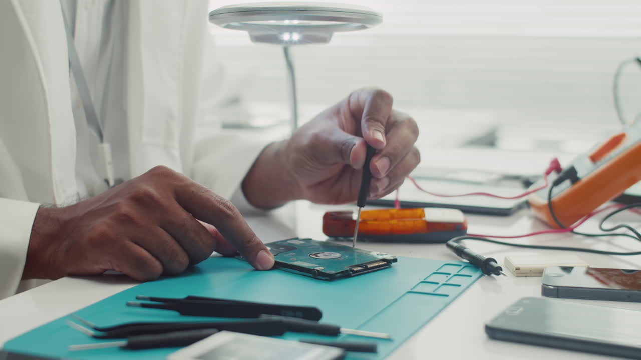 Hands of Technician Repairing Hard Drive with Screwdriver
