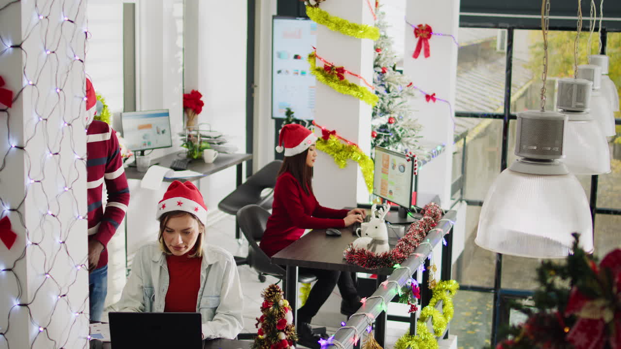Office decorated for Christmas with coworkers in santa hats
