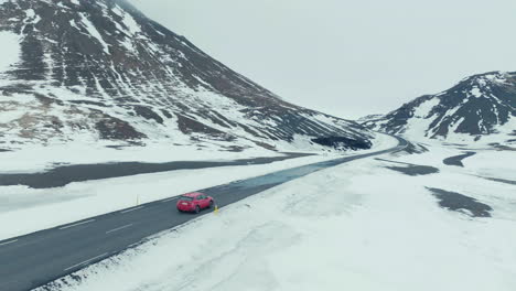 Coche-Rojo-En-Carretera-Mojada-En-El-Paisaje-Montañoso-Nevado