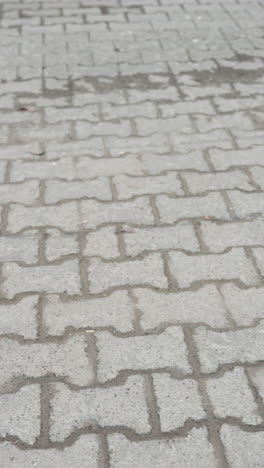 vista en primer plano de dos personas caminando por una acera pavimentada, mostrando sus zapatos y el movimiento de sus piernas