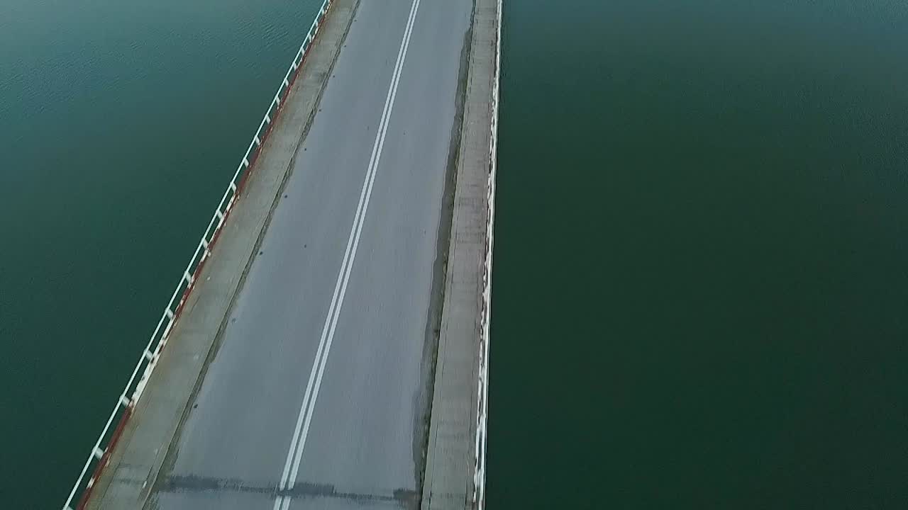 panorámica vertical en un dron delantero disparado sobre un puente en un lago en grecia durante la hora azul