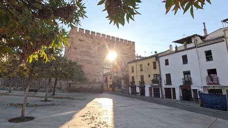 beautiful sunrise shining through the puerta de elvira in granada, albaicin spain. autumnal leaveas in the foreground. plaza del triunfo