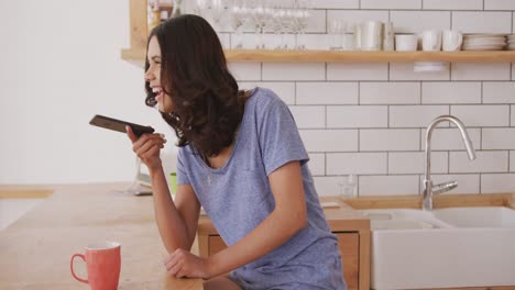 mujer hablando por teléfono inteligente en la cocina