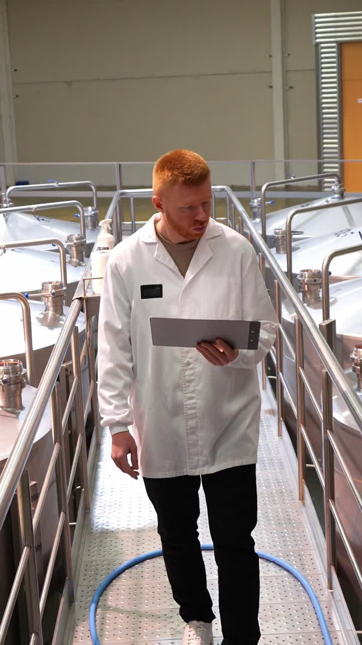 Factory Worker Inspecting Stainless Steel Tanks