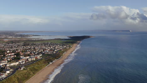 pan cinematográfico aéreo a través del canal de la mancha vista de la tarde de la playa, la carretera y la isla de wight de bournemouth reino unido