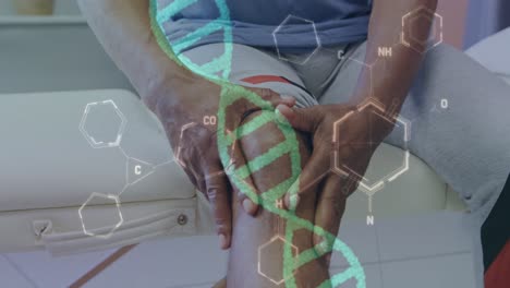 Animación-De-La-Cadena-De-ADN-Y-Datos-Médicos-Sobre-Un-Paciente-Afroamericano-Sosteniendo-La-Rodilla