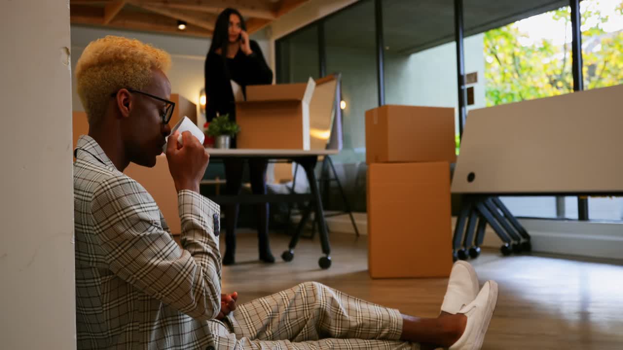 Side view of young black businessman drinking coffee in modern office 4k