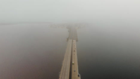 Aerial-shot-of-cars-and-trucks-move-across-a-multilane-long-raised-bridge-over-a-massive-area-of-water