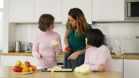 dos niñas con síndrome de down están aprendiendo a cocinar con su madre en la cocina en casa