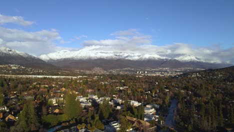 Disparo-De-Un-Dron-Sobrevolando-Los-Suburbios-Ricos-De-Santiago-De-Chile-Con-Las-Montañas-De-Los-Andes-Cubiertas-De-Nieve-Al-Fondo