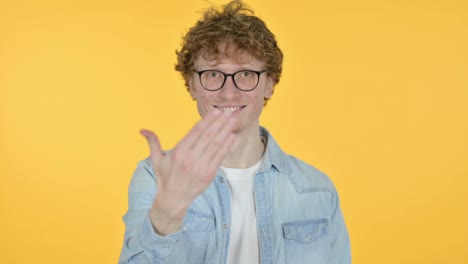 roodharige jonge man die wijst en uitnodigt, gele achtergrond