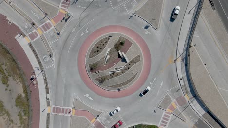 Drone&#039;s top-down view of a busy roundabout with personal and commercial vehicles in the early afternoon