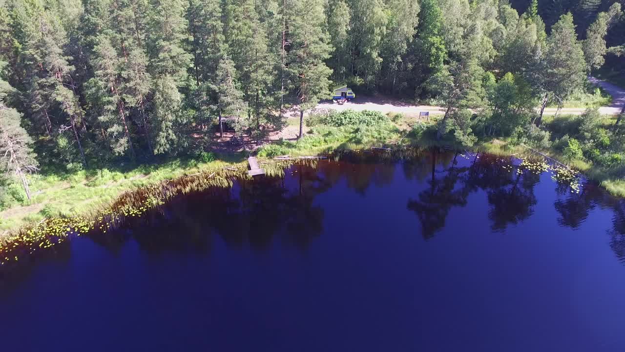 Camping i en bus ved en sø i Sverige, omgivet af skov.
