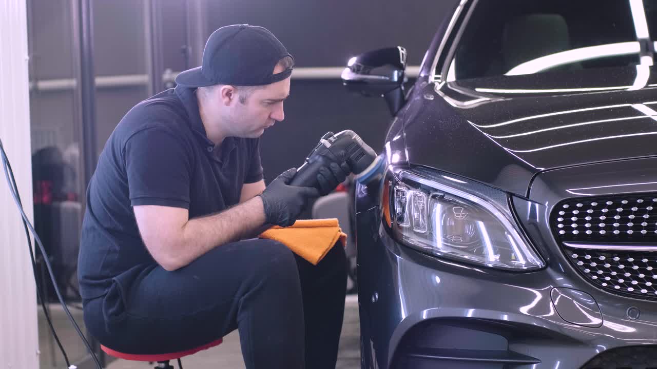 trabajador pulir un coche negro. detalle del coche - el hombre está usando maquinaria pulidores de automóviles mantenimiento para eliminar marcas reparación de acuerdo con la superficie de la pintura del coche antes de contin