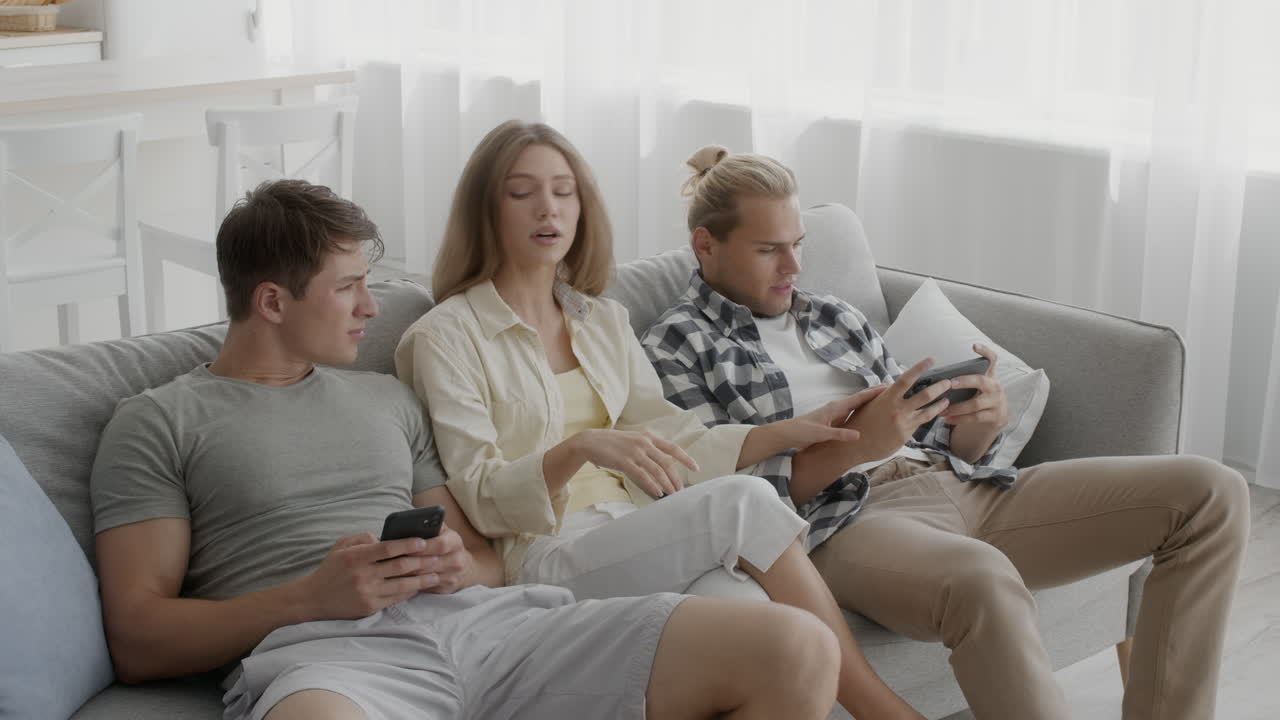 친구 들 이 소파 에 앉아 전화 를 사용 하고 있다