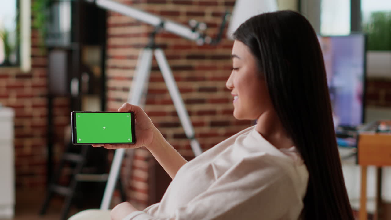 초록색 화면 을 가진 스마트폰 을 들고 있는 여자