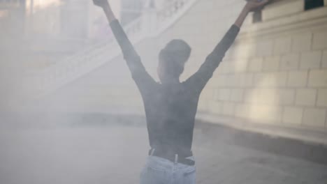 joven afro mujer delgada en la niebla. mujer afro americana corriendo libremente afuera con granada de humo - holdimg dos granadas colores blanco y negro y huyendo sin preocupaciones. vista rara