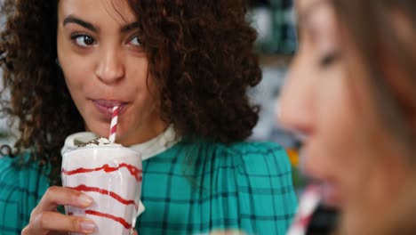 mujeres sonrientes tomando un batido con paja