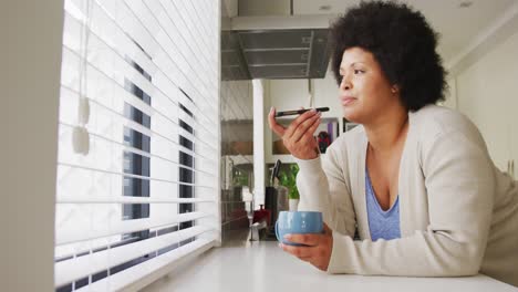 Video-De-Una-Feliz-Mujer-Afroamericana-De-Talla-Grande-Tomando-Café-Y-Usando-Un-Teléfono-Inteligente